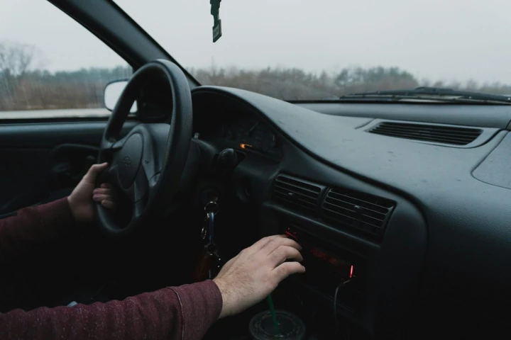 a cars console with a man's hand on the steering wheel
