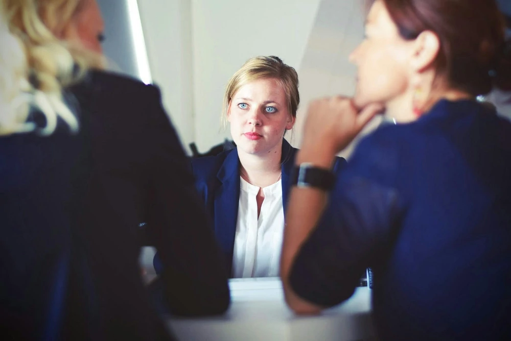 A woman looks at two people interviewing her